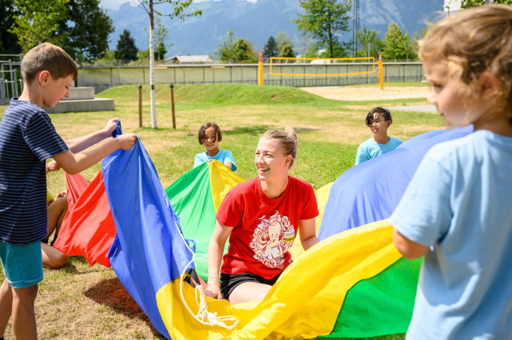 Leiterin im Betreuer-Shit machtFallschirm-Spiele mit den Kindern.